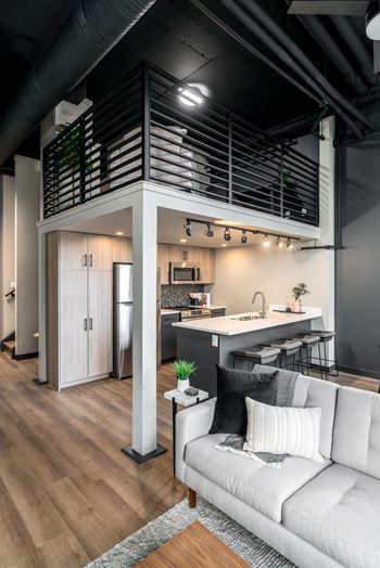 A modern kitchen with a white couch and wooden floors.at Raymond Block, Edmonton, AB T6E 3R7
